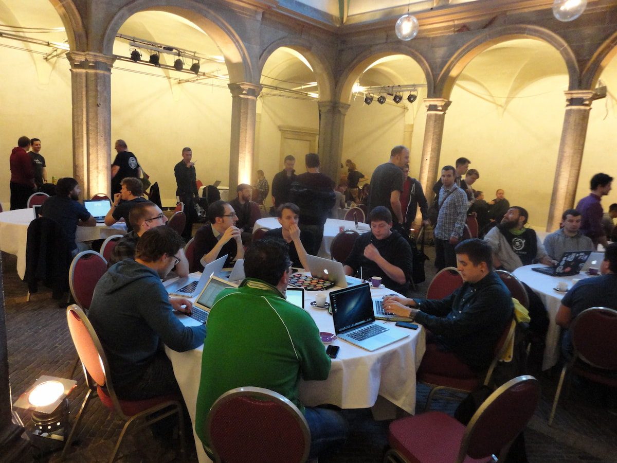 People sitting and standing around round tables at the WCEU 2013 contributor day. I sit in the middle of the picture among them.