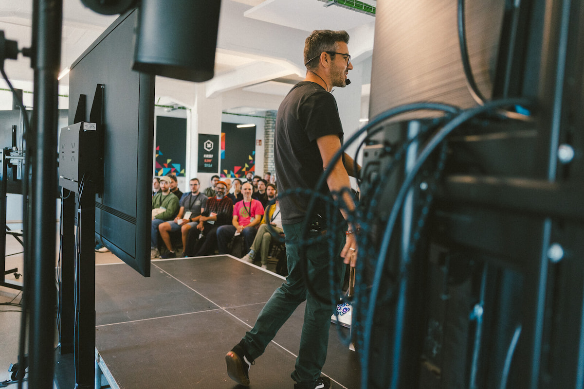 Bastian standing on the stage, photographed from the back so you can see the crowd behind him.